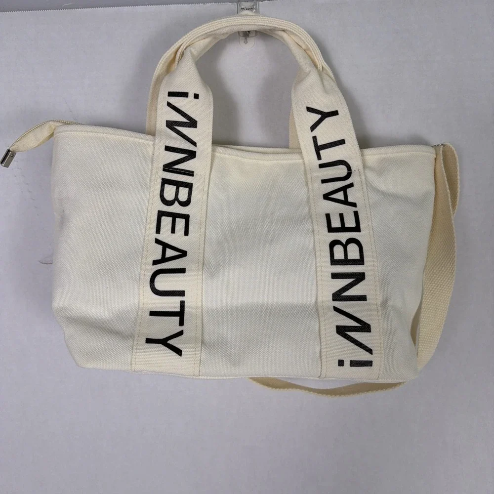 iNN BEAUTY bag off white tote bag with black letter branded straps.